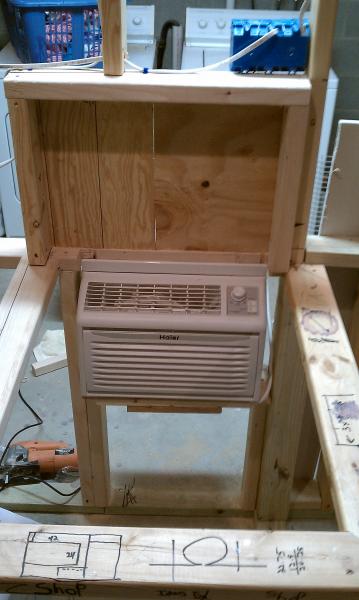 The air conditioner is dryfit in its aperture.  Above it is the back panel of the draft box.  The 2x4s protrude from the wall to form a cleat that the removable box will rest on.