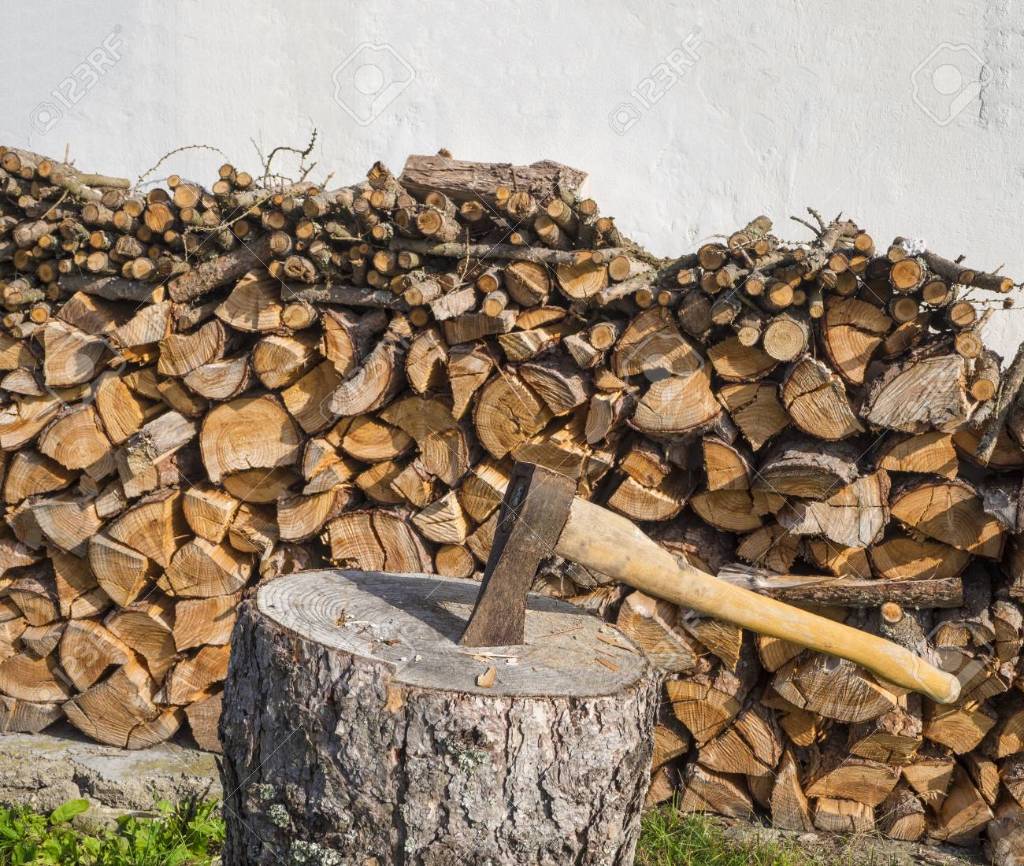 88273372-axe-on-the-chopping-block-with-chopped-wood-pile-leveled-on-white-wall.jpeg