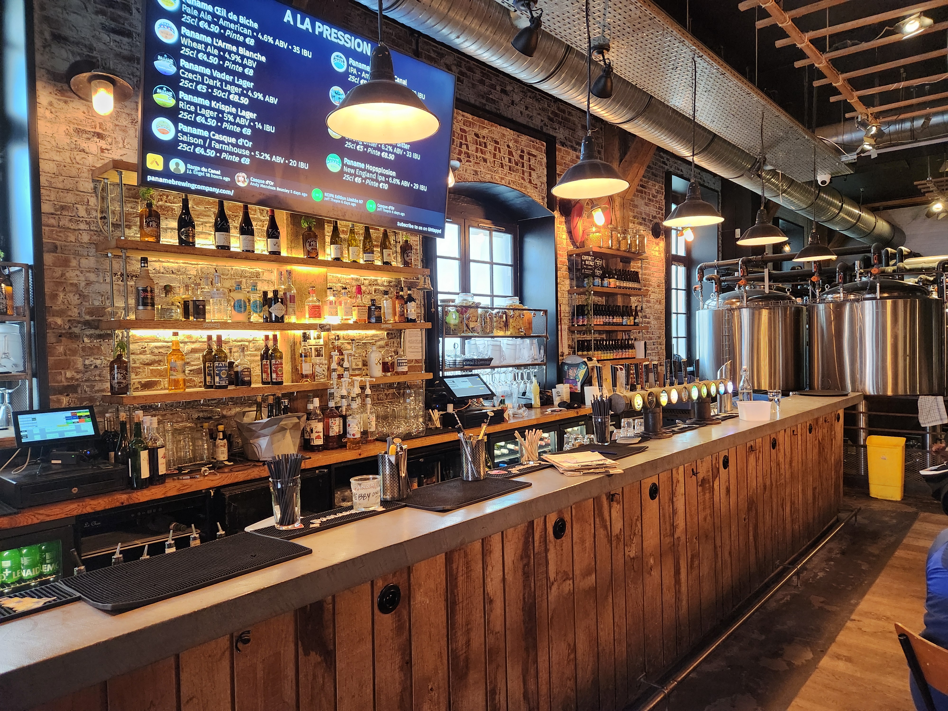 A taproom serving area in the foreground with brewing equipment in the background. 