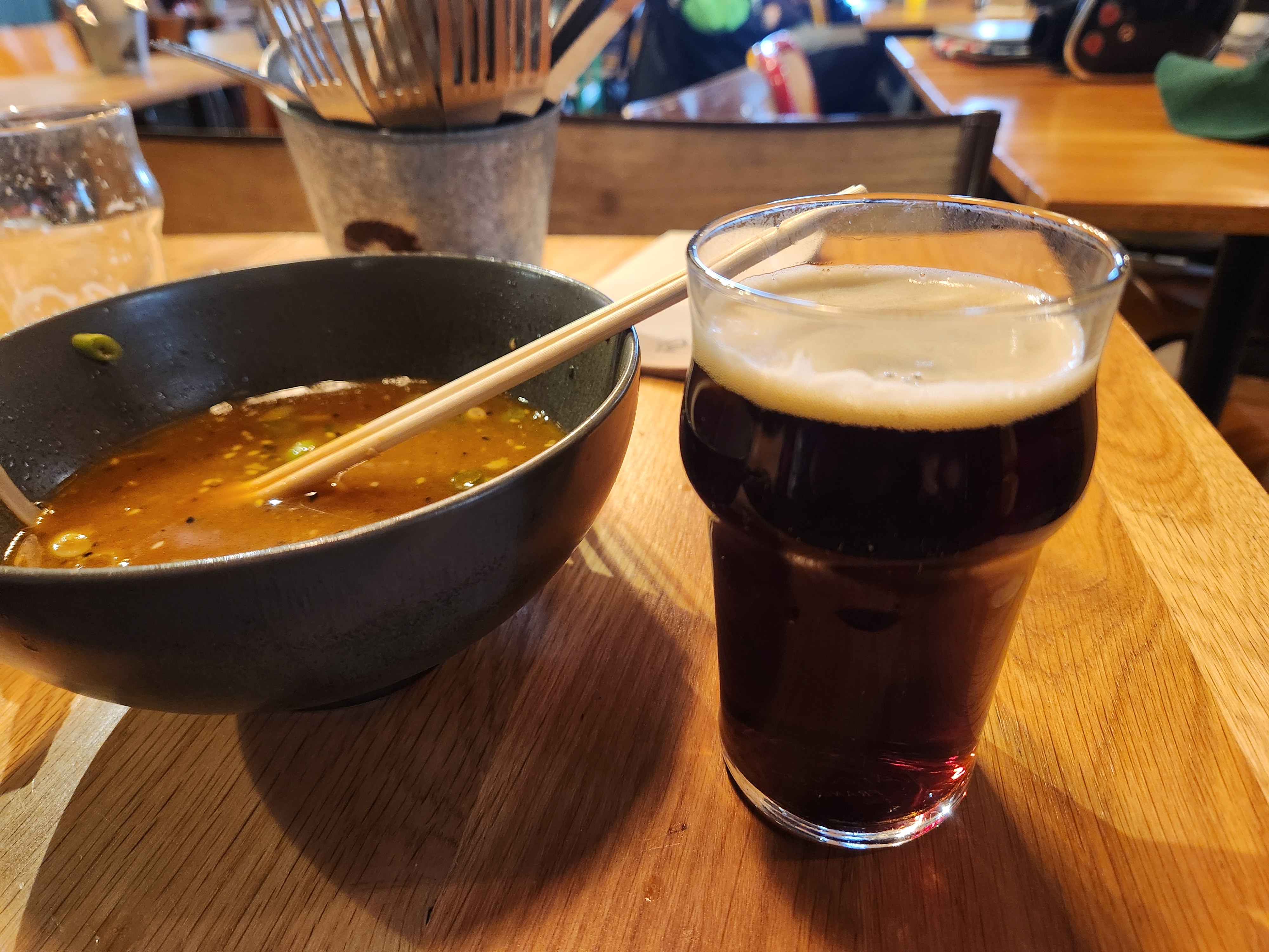 A glass of beer and a bowl of Ramen